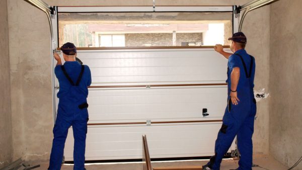 Two technicians installing a new residential garage door inside a garage