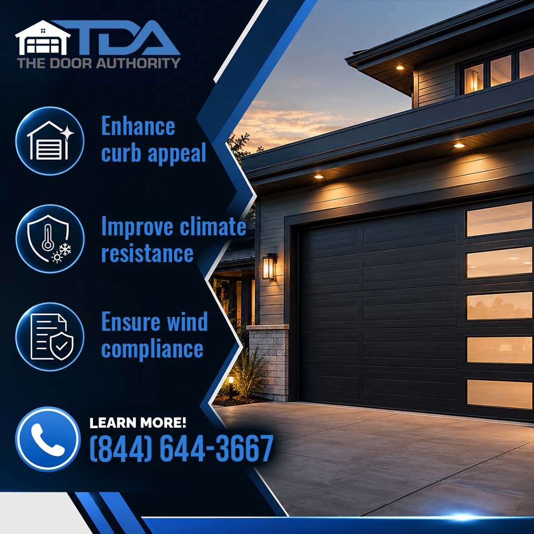 Exterior view of a modern dark grey residential garage door with frosted vertical side windows lit by warm soffit lighting.