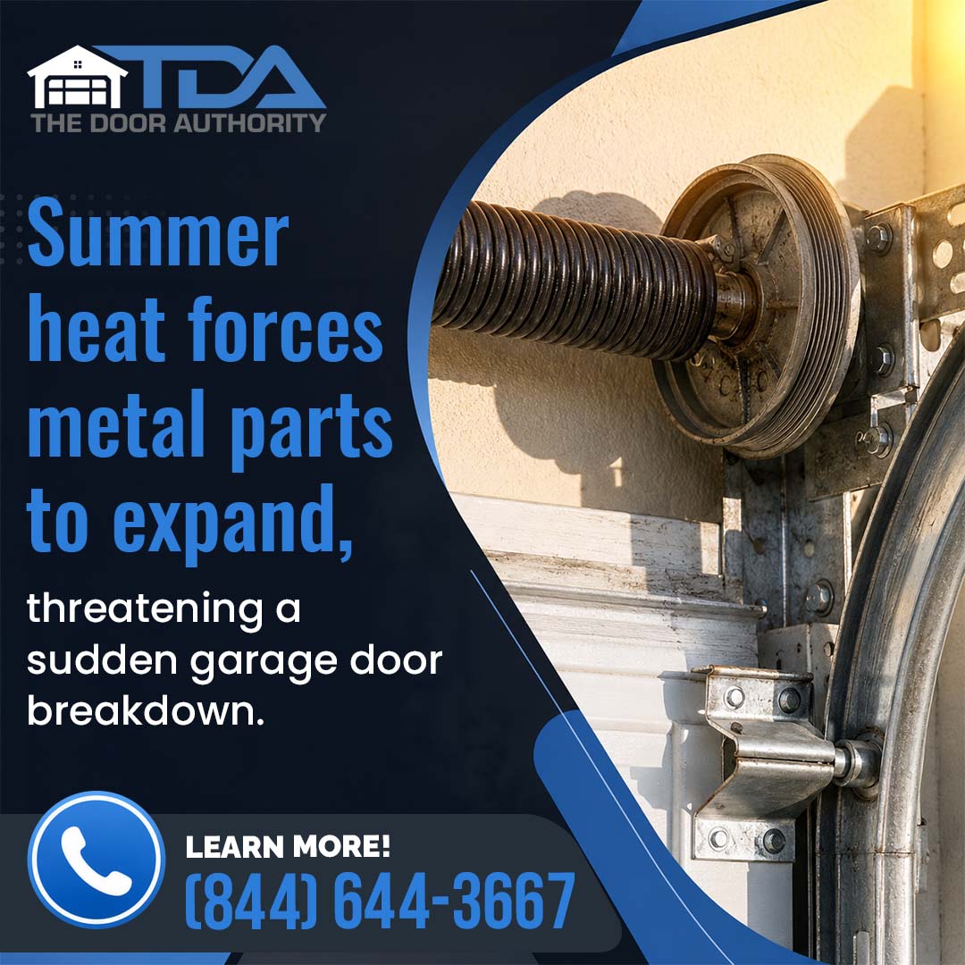 A close-up view of a garage door torsion spring, cable drum, and track assembly bathed in bright sunlight, with warning text about summer heat effects.